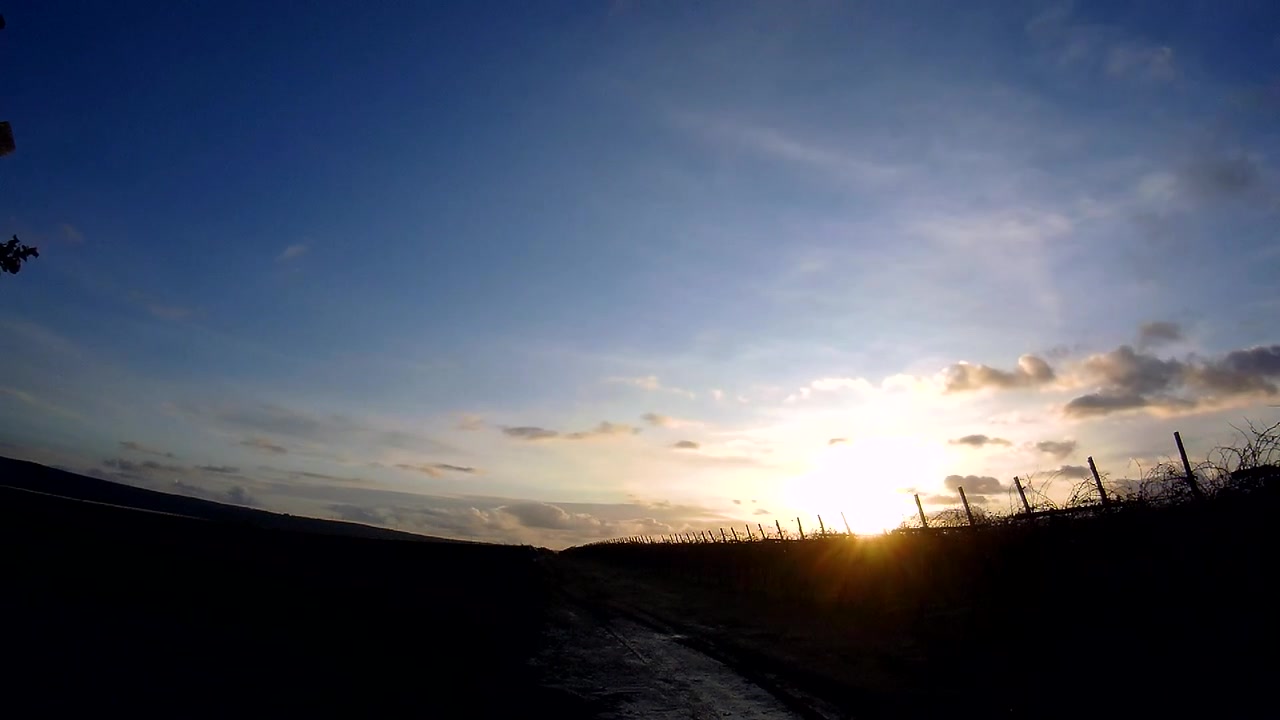 Nuvens de pôr do sol em timelapse flutuam sobre um caminho rural na encosta ao longo da Costa Amalfitana, na Campânia, Itália. Silhuetas escuras contrastam sob o céu do entardecer