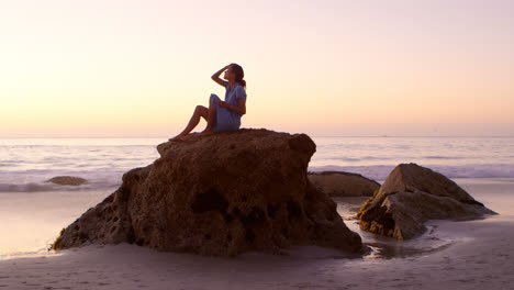 mujer relajándose en una roca en la playa 4k