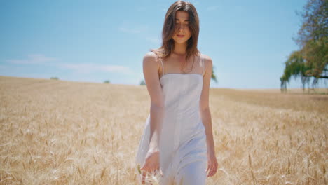 relaxed woman strolling sunlight farmland. serene lady touching wheat at harvest