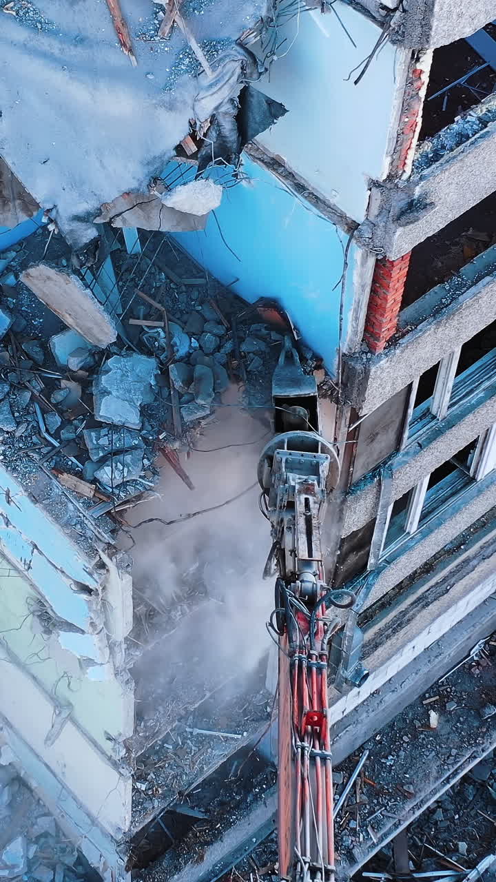 The removal of house wrecks after an earthquake. Dismantling of collapsed structures.Up view of excavator work with wrecks of ruined buildings. Vertical video