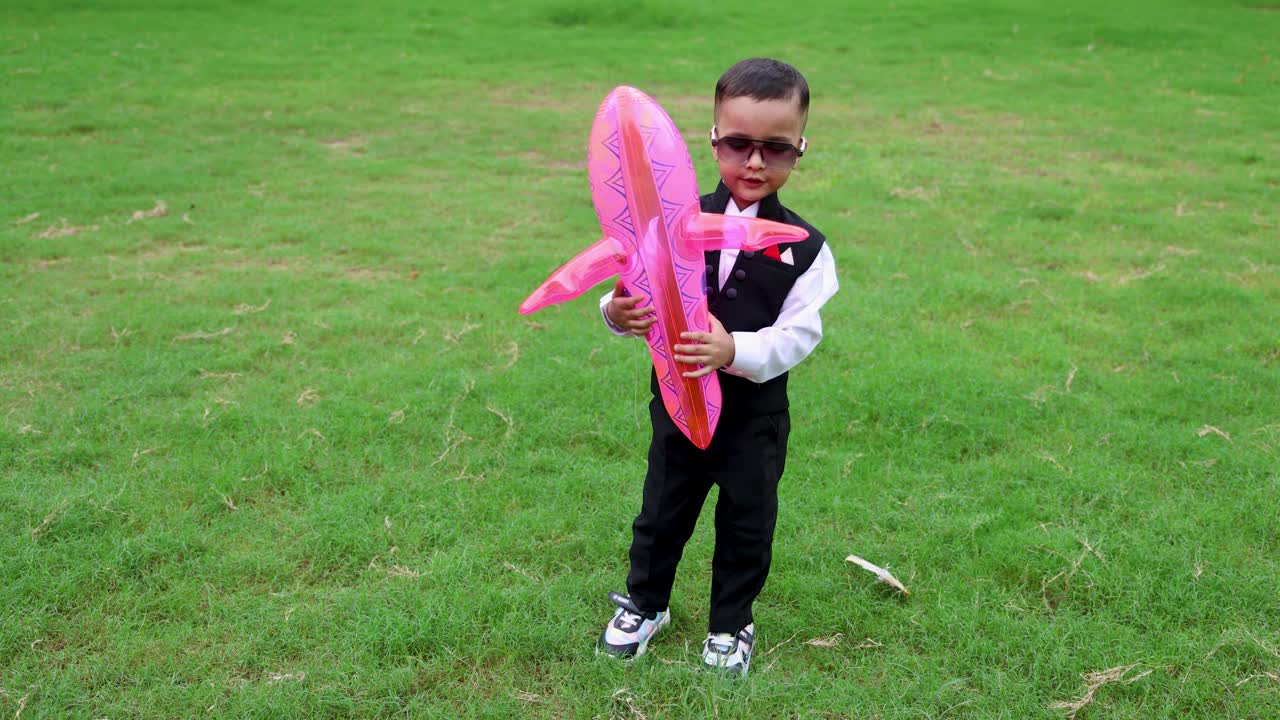 niño indio pequeño con cara alegre y globos en un entorno matutino al aire libre