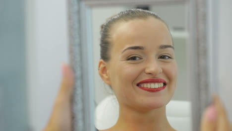 a woman looks in the mirror and enjoying her smile