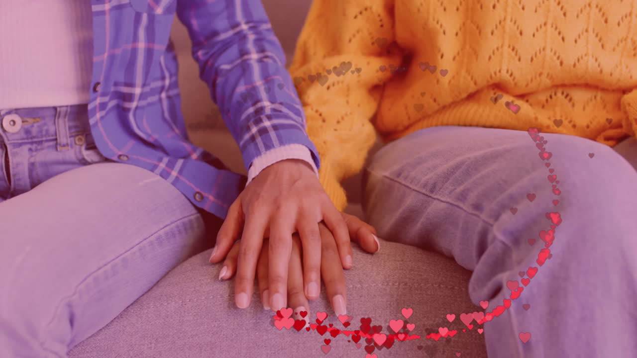 animación de los corazones sobre feliz pareja diversa tomándose de la mano en casa
