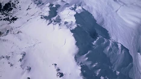 toma aérea de drones volando sobre el paisaje montañoso cubierto de nieve sobre la ciudad de la estación de esquí en verbier, suiza