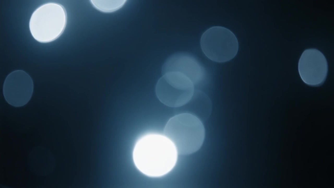 Cerchi di luce bokeh blu astratti in movimento su sfondo scuro