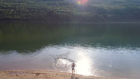 kobieta bawiąca się ze swoim psem w pobliżu brzegu rzeki w słoneczny dzień 4k 4k