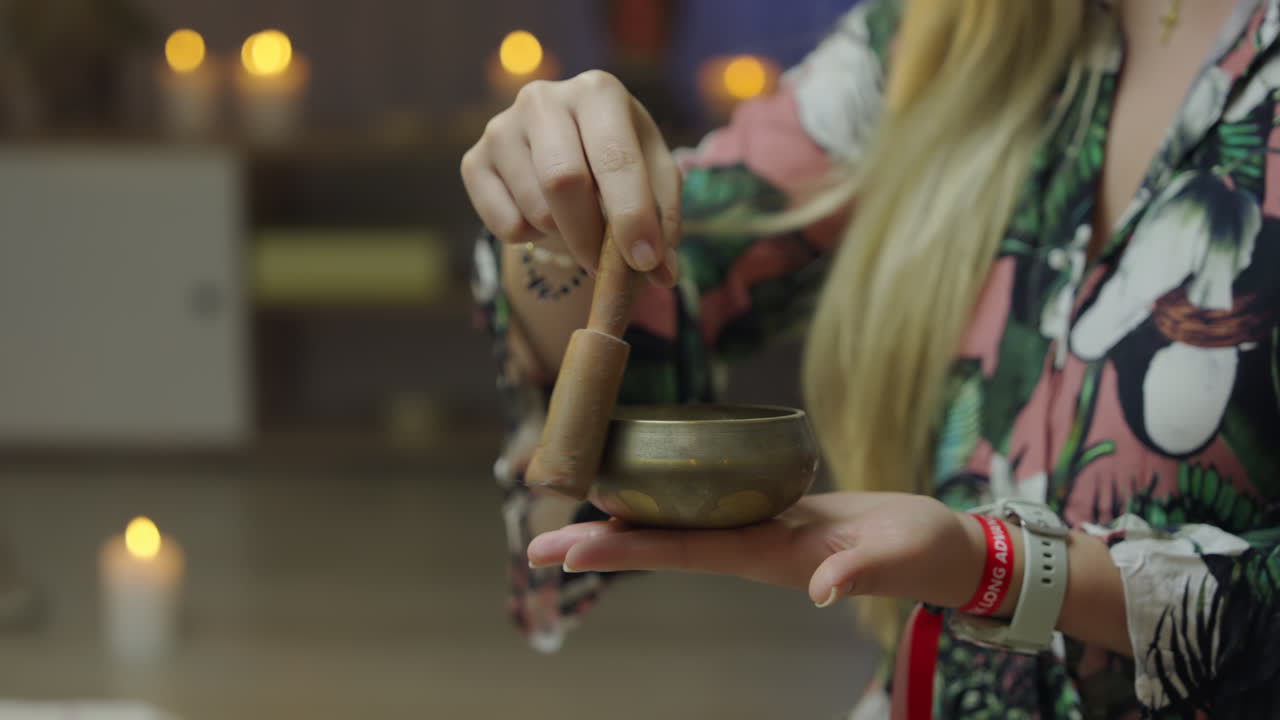 Blonde woman relaxes with Tibetan singing bowl in cozy living room