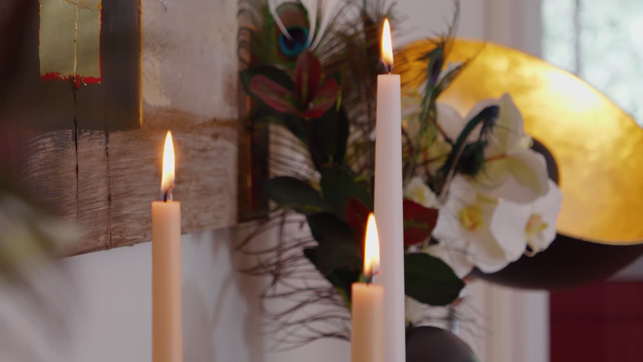 lento disparo revelador de velas ardiendo en un aparador rodeado de plantas