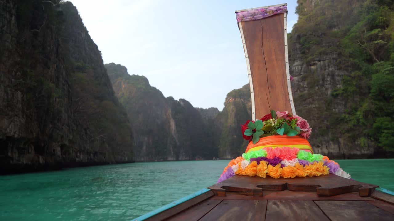 Front of a longtail boat driving into a bay, with mountains either side, thailand Koh Phi Phi