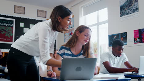 Female-Teacher-Helping-Female-Pupil-Using-Computer-In-Classroom