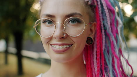 smiling woman with colorful dreadlocks and glasses