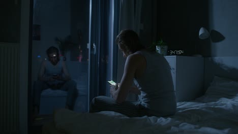 man using phone in bedroom at night