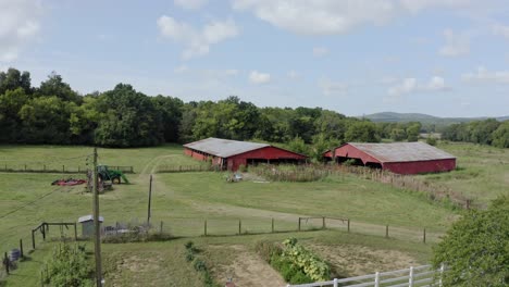 4K-aerial-view-of-overgrown-southern-farm-with-barn-and-tractor-in-field