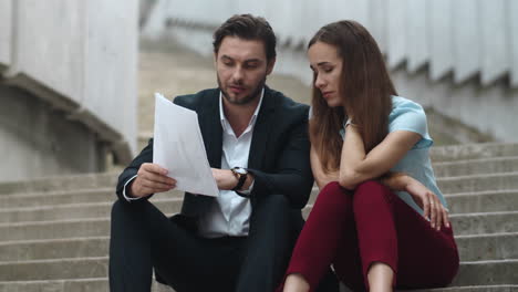 Tired-business-man-and-business-woman-looking-at-business-papers-on-street