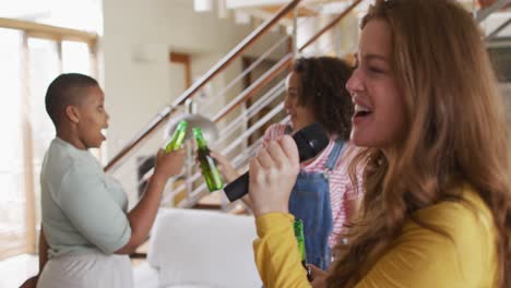grupo diverso de amigas divirtiéndose cantando karaoke y bebiendo cerveza en casa