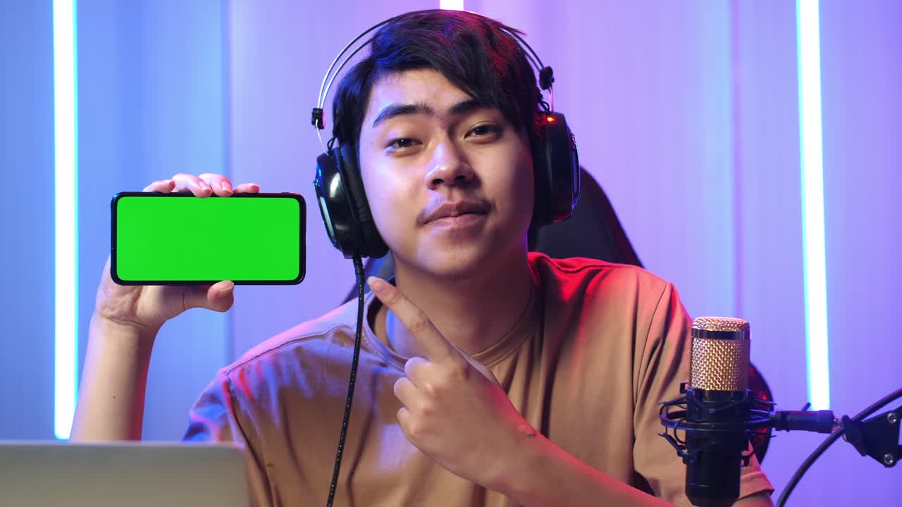 Asian Man Holding Mobile Phone With Mock Up Green Screen While Live Stream