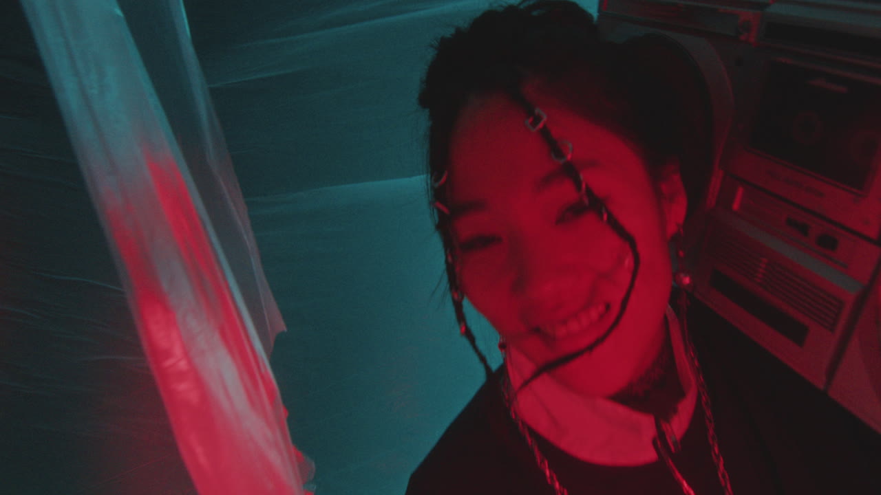 Cheerful Asian Girl in 90s Outfit Holding Boombox and Dancing in Neon Light