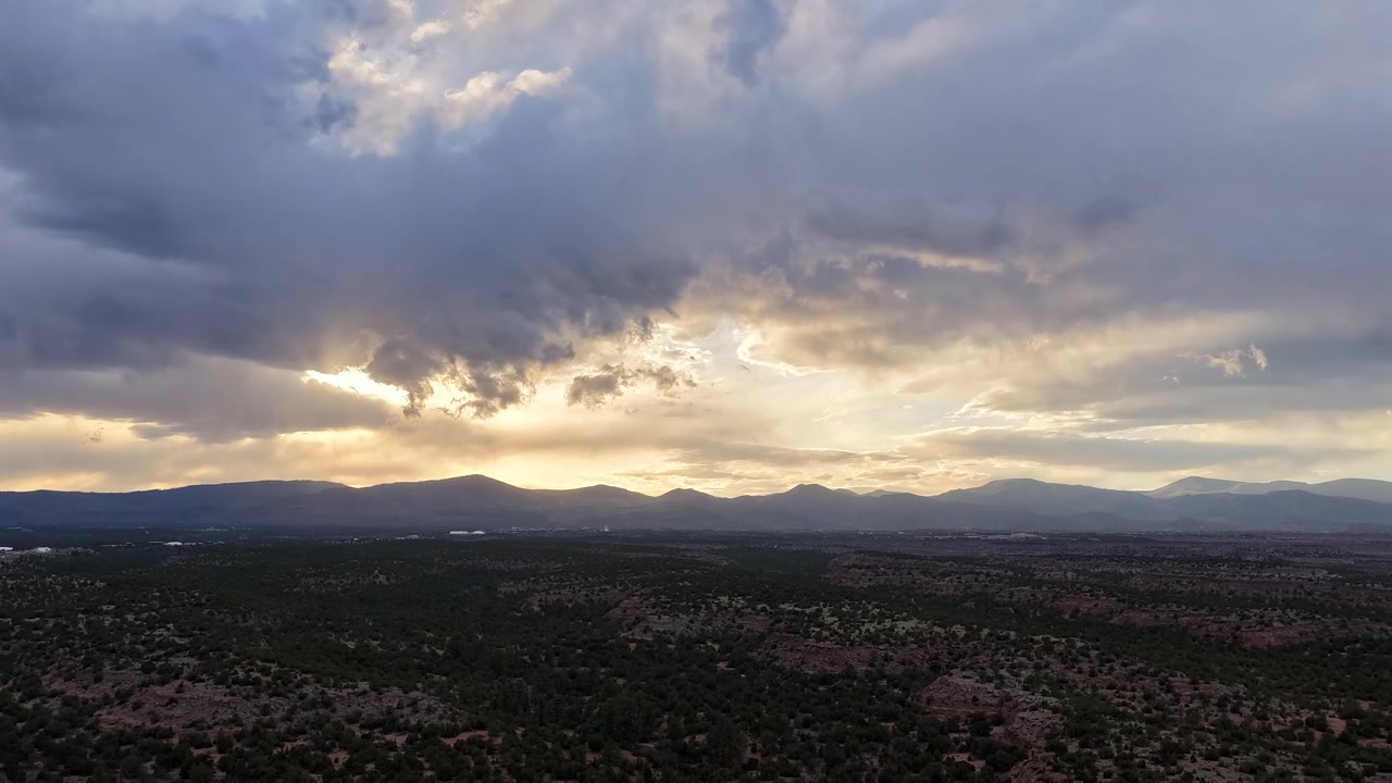 4K drone timelapse captures mesmerizing clouds and golden sunbeams rippling over rugged southwest mesas. Cinematic aerial skyscape reveals radiant light rays and dynamic desert nature transitions.