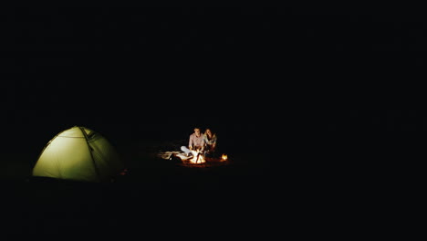 top view of a young couple the tent and campfire around dark only a fire and tent refresh people