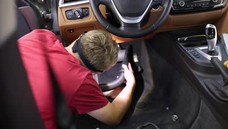 man vacuuming car interior during professional detailing