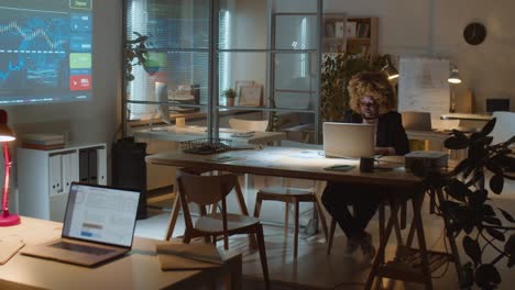 african american businesswoman working in dark office at night