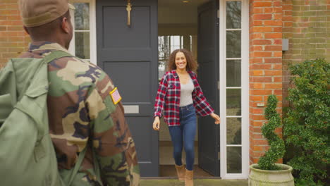 american soldier in uniform returns home to family on leave hugging wife and children outside house