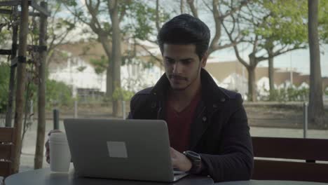 Serious-man-working-with-laptop-in-outdoor-cafe