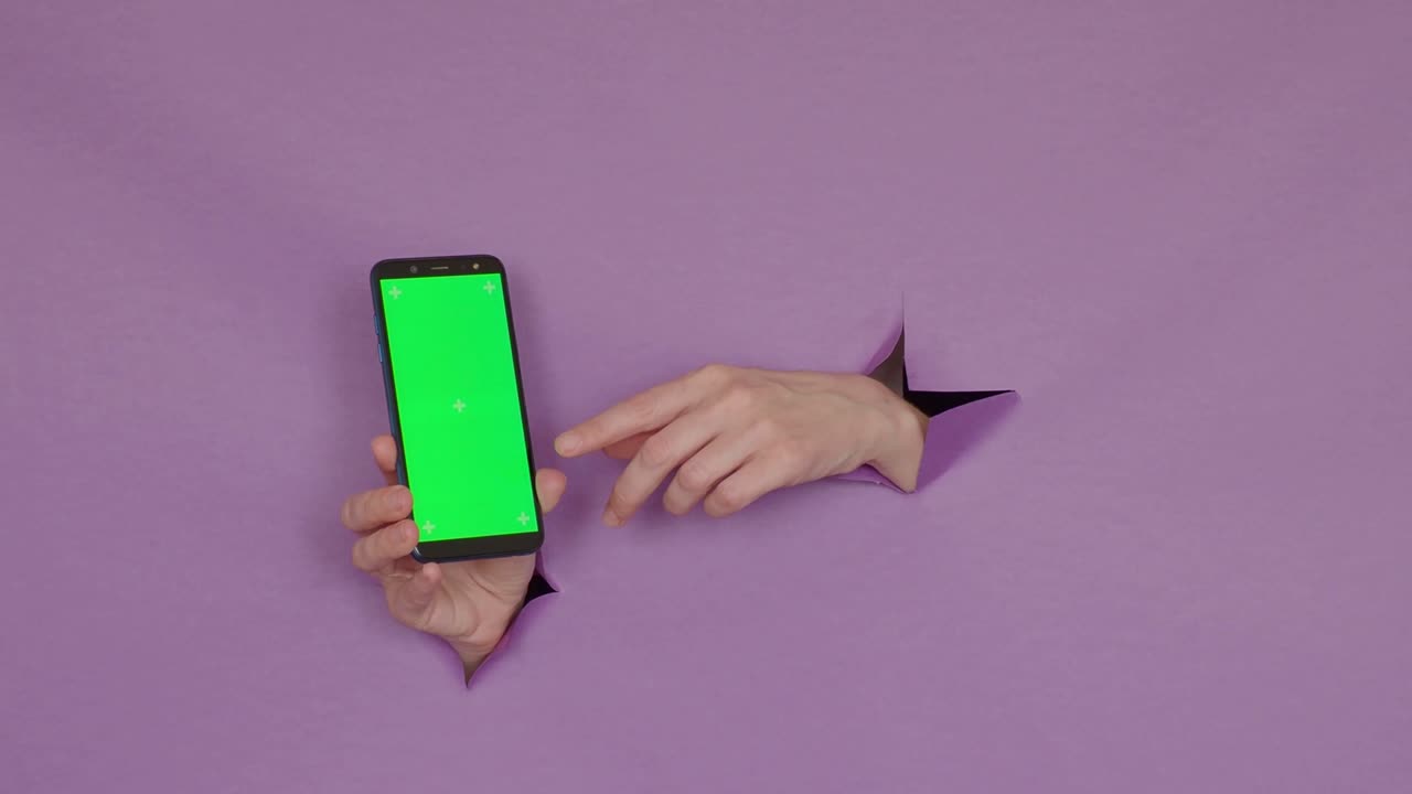 teléfono con una pantalla verde en las manos, sobre un fondo púrpura