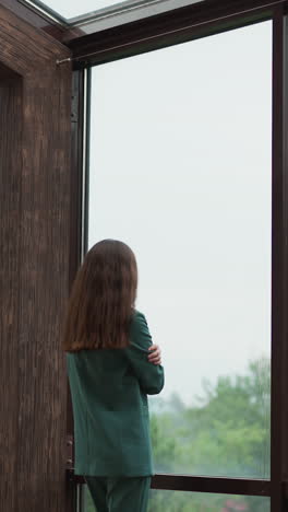 businesswoman wrapped in own embrace. woman worker spends quiet moment on terrace with panoramic windows seeking solace in solitude. modern office building