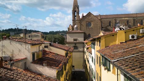 drone flies between tight alley way rising to the bell tower of basilica of santa croce in florence italy