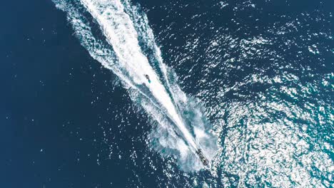 jet ski and surf rider on jet skiing on tropical blue and green sea waterscape. top down aerial footage of sport activity with ocean waves ripple. beautiful high adrenaline and extreme sports scene.