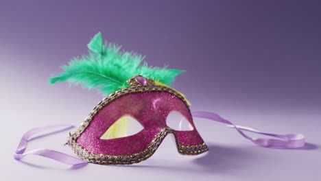Video-Einer-Rosafarbenen-Karnevalsmaske-Mit-Grünen-Federn-Auf-Weißem-Und-Violettem-Hintergrund