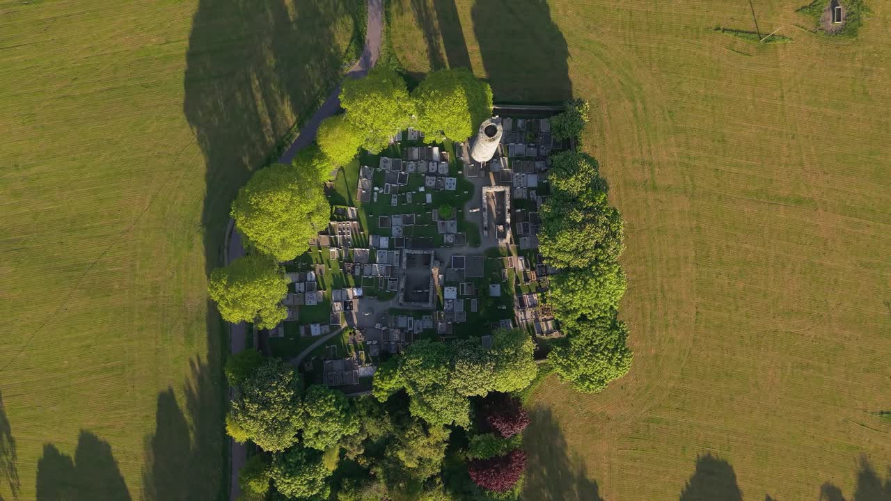 Ruins of Monasterboice in Ireland under a serene sky, lush green surroundings