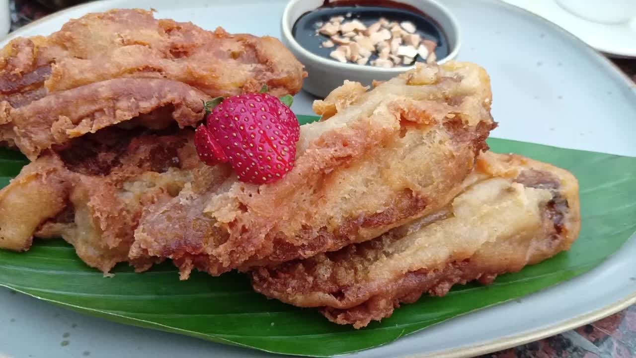 Ripe fried bananas are ready to be served with strawberry toppings and chocolate peanut sauce