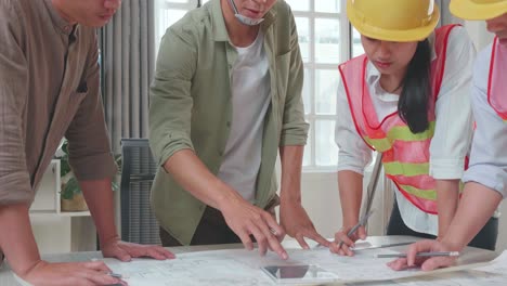 three asian engineers with helmets presenting work on the tablet to a man at the office