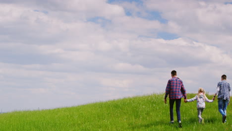 A-Group-Of-Children---Two-Teenage-Boys-And-A-Girl-Of-Six-Years-Climbing-Up-The-Green-Hill-Together