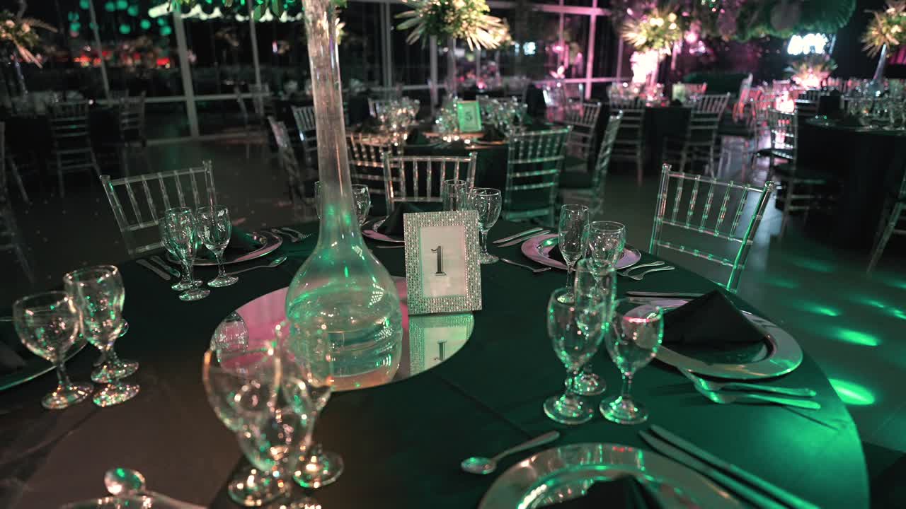 Mesa preparada para una elegante cena de gala con manteles negros, vajilla reluciente, copas de cristal y centros de mesa florales, relámpagos en movimiento, lista para una boda sofisticada o una recepción de lujo