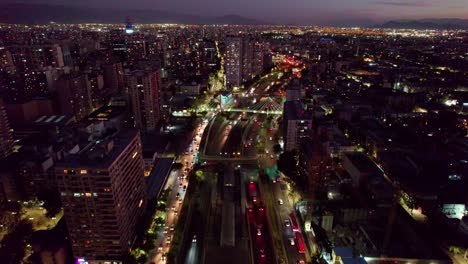 Downtown-Santiago-highway-cityscape-at-night-with-speeding-traffic-in-colourful-illuminated-aerial-view-over-Chile