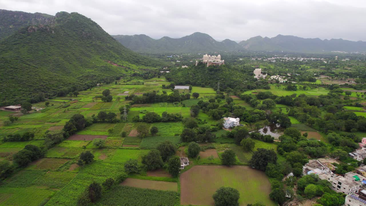 ascenso de drones centrado en el palacio del monzón sajjangarh en la base de las verdes colinas tropicales de las afueras de udaipur