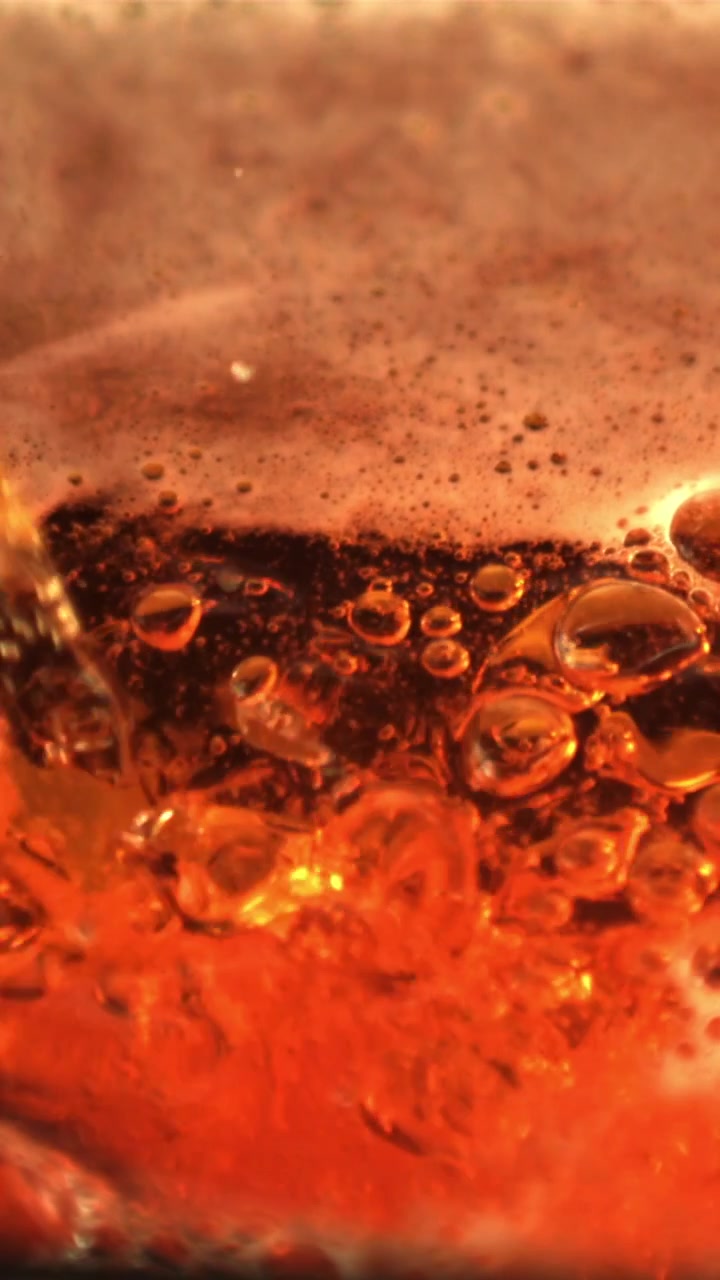 Macro di bevanda ambrata effervescente con bollicine frizzanti