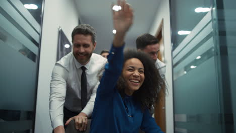 multiracial coworkers team celebrate business deal race office chair in company.