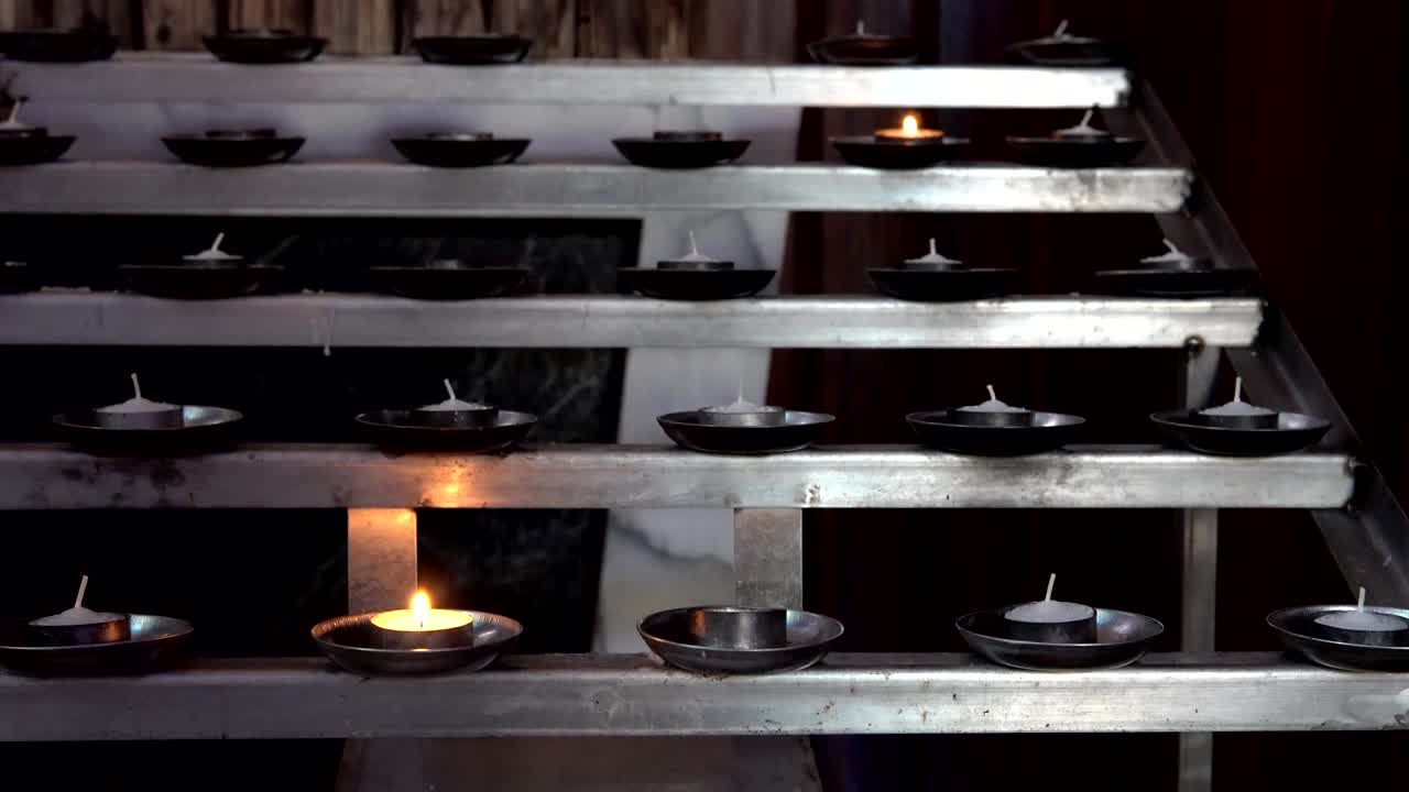 Udsigt til kirke. Glasmalerier i kirke med træbænke. Levende lys.