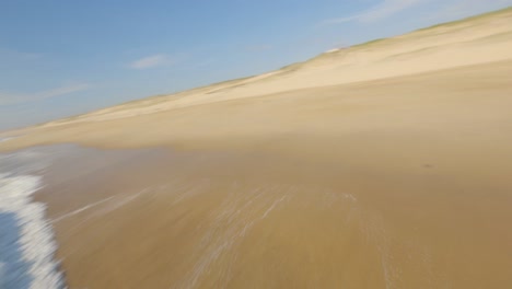 Two-surfers-with-surfboard-walking-along-sea-shore-of-deserted-beach,-Landes-in-France