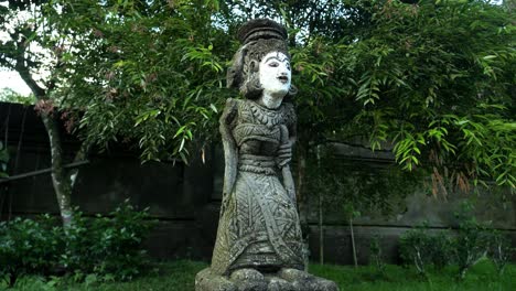 Parallaxenaufnahme-Einer-Religiösen-Statue-Im-Tempel-Pura-Tirta-Empul-Auf-Bali-In-Indonesien-In-Ubud-In-Einem-Wunderschönen-Garten-Mit-Blick-Auf-Bäume-Und-Blätter-In-Zeitlupe