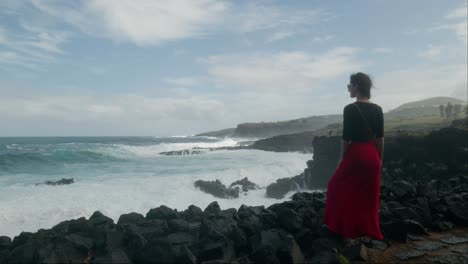 woman in a red dress, enjoying sun and ocean at rocky playa de las americas beach in tenerife