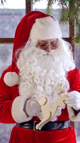 santa claus standing in specially decorated room, holding wooden dear near the new year tree. christmas spirit concept close up portrait. christmas eve. new year is coming. vertical video
