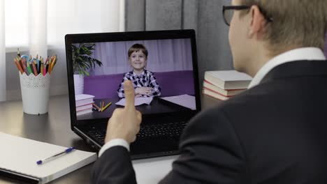 man teacher making video call on laptop with little pupil. distance education