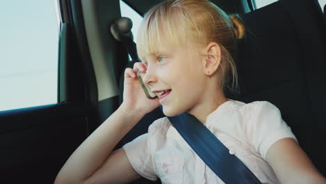 funny girl 6 years old speaks on the phone rides in the back seat of the car it is fastened with a s