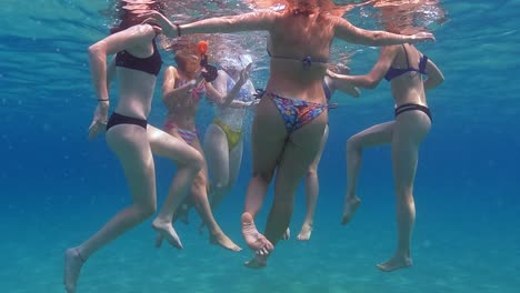 Underwater-slow-motion-scene-of-group-of-female-friends-swimming-in-crystal-clear-tropical-seawater