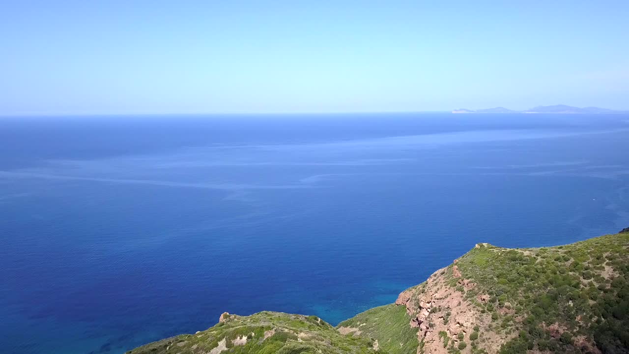 Drone Aerial shot flying towards the cliffs ending on a stunning blue Mediterranean Sea. the cliffs are covered by a wonderful green vegetation